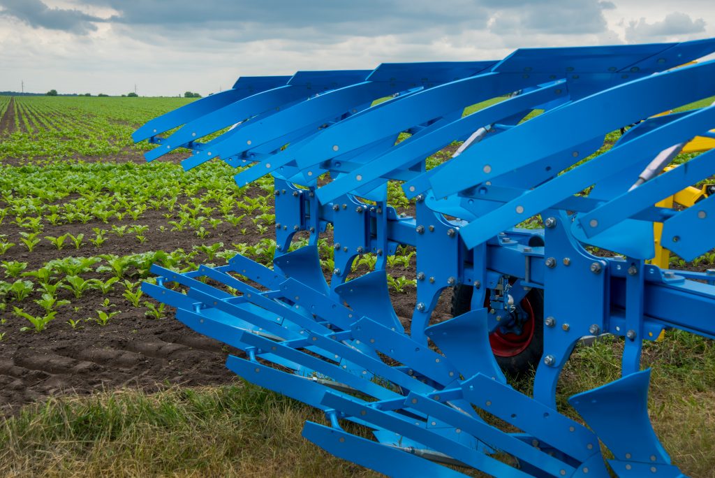agricultural plow for deep plowing on a tractor trailer. a close up of a blue plow for plowing .