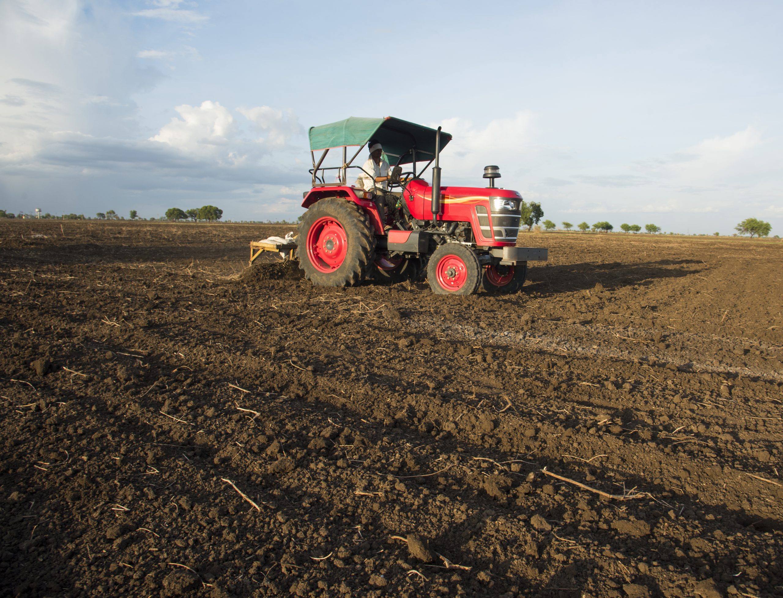 farmer with tractor preparing land for sowing with cultivator